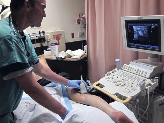 A clinician performing ultrasound scanning of a patient’s leg.